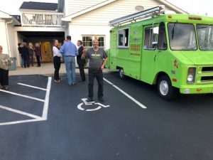 Man posing for camera outside near food truck at charity event
