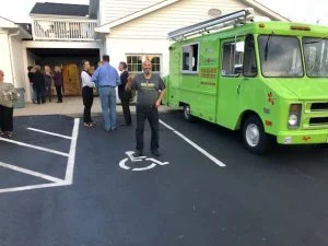 Man posing for camera outside near food truck at charity event