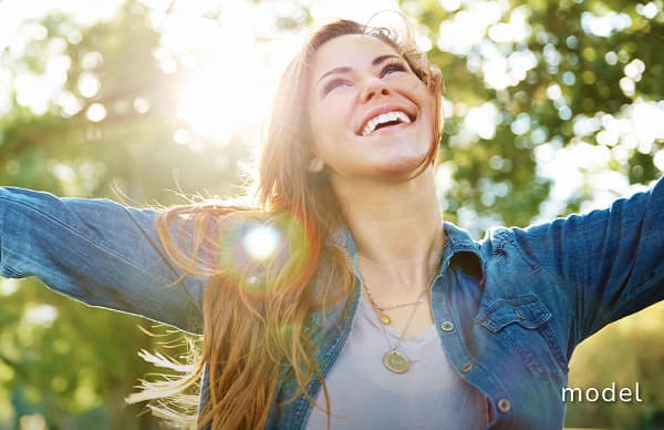 Brachioplasty (Arm Lift) model of woman outside looking up at the sky with arms out smiling