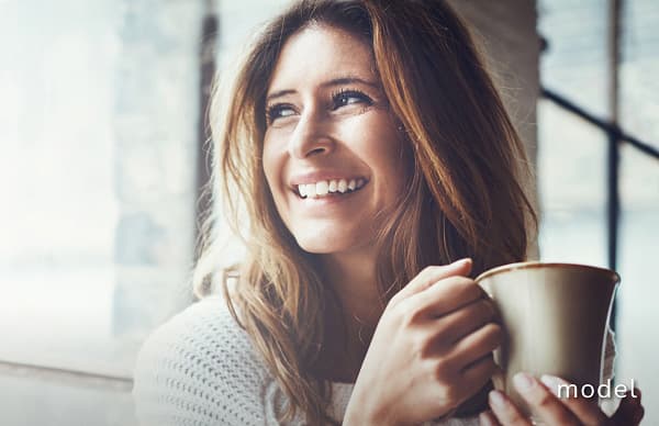 Fat Transfer (Fat Grafting Injections) model of woman looking at window away from camera holding a coffee mug