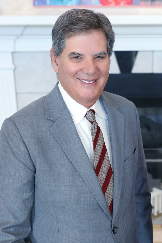 Portrait of Dr. Mark Mandell-Brown smiling wearing a gray suit