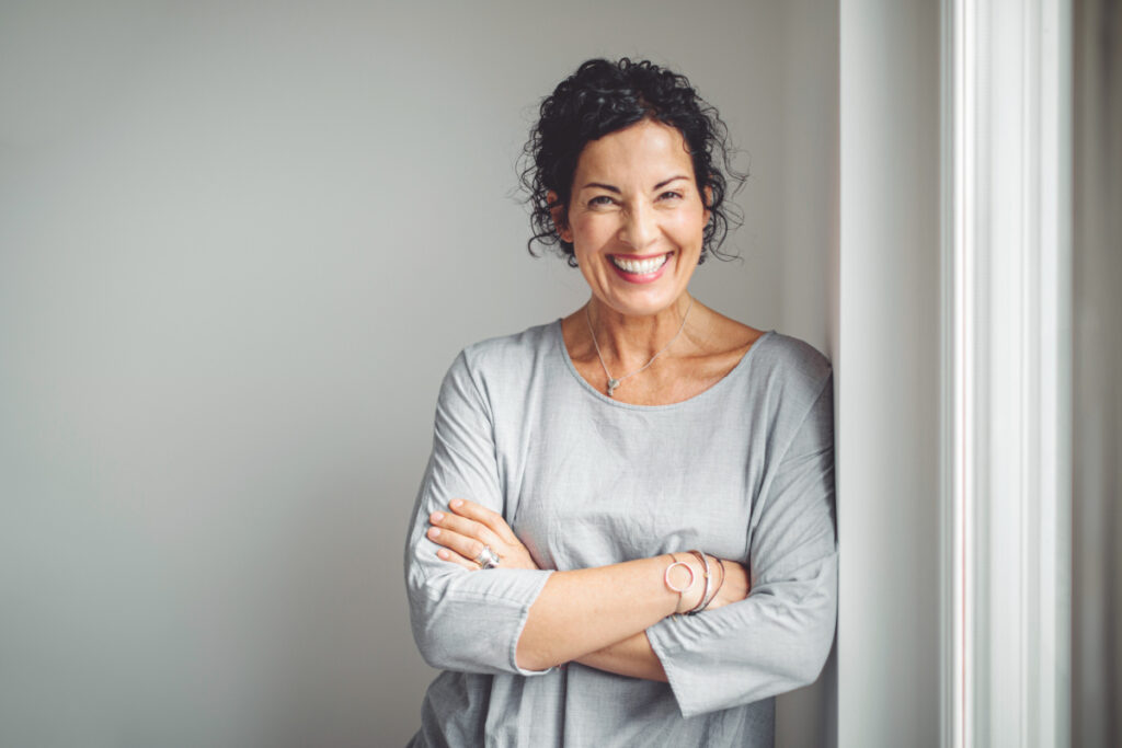 Mature woman leaning against wall and smiling