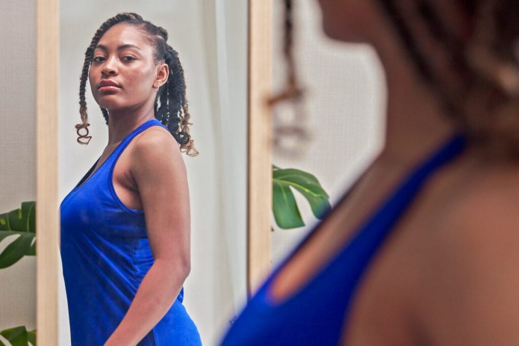 Woman looking in the mirror considering a revision plastic surgery procedure