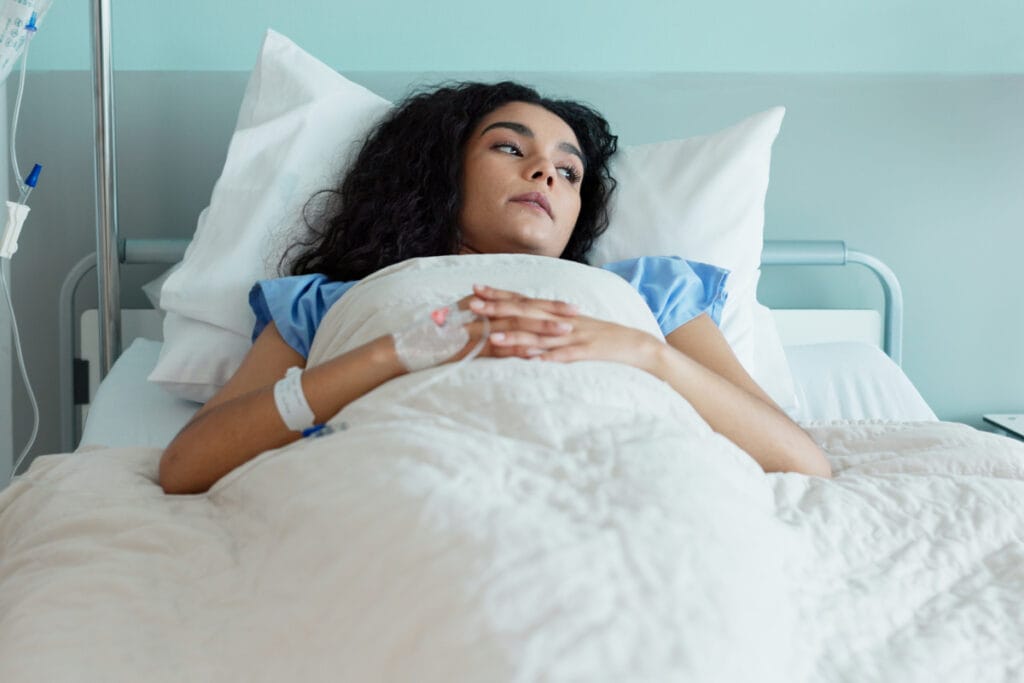 Woman lying in bed recovering after long mommy makeover surgery