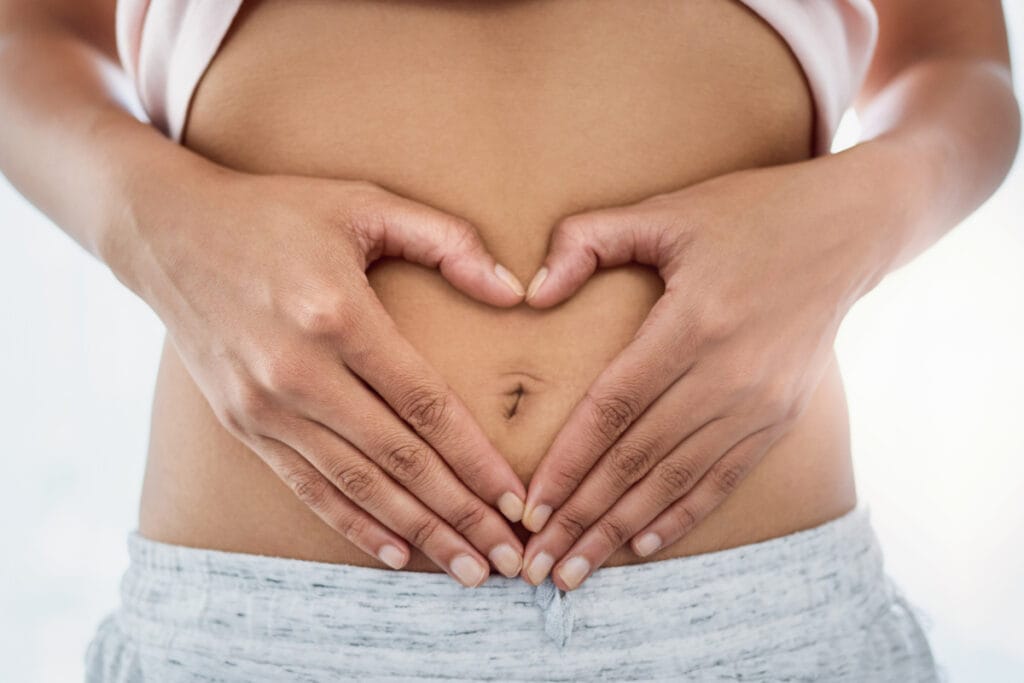 Close up of adult woman with hands around belly button
