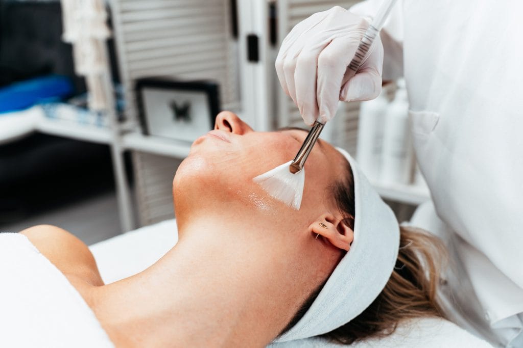 Gloved provider applying a Dayton chemical peel to a woman's face